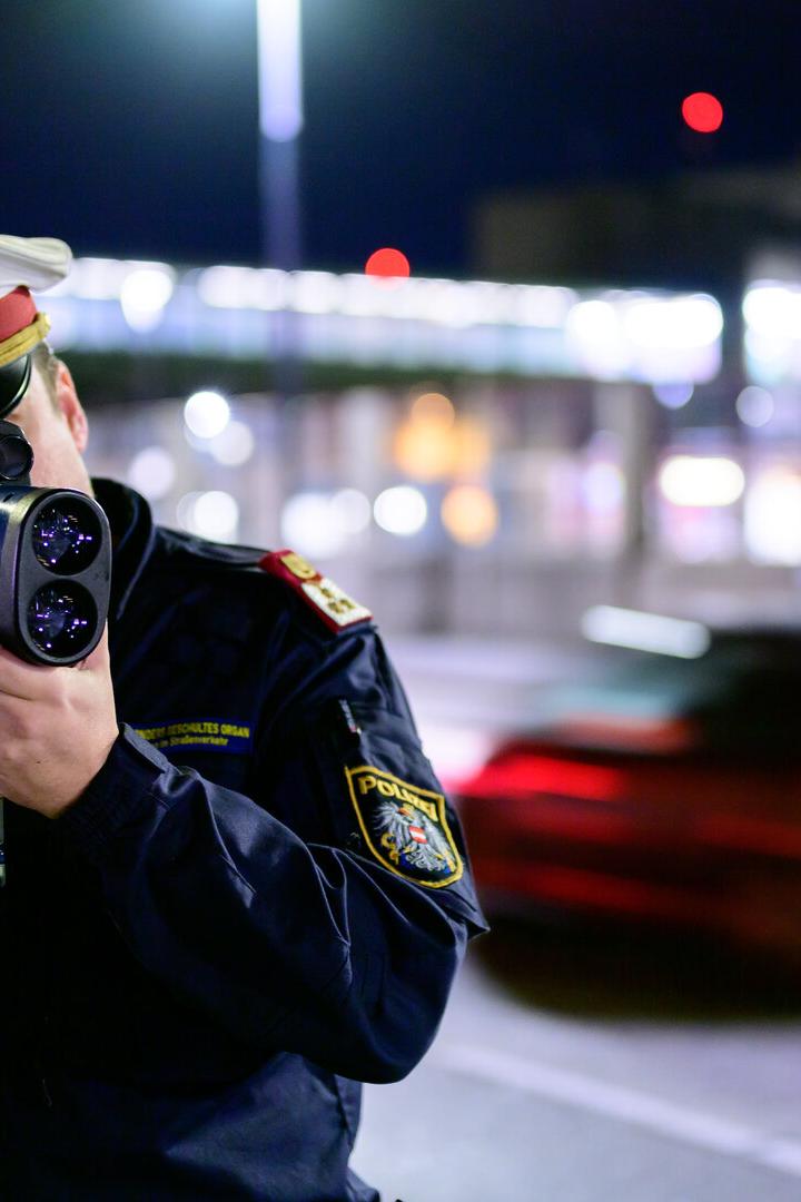 Ein Polizist misst mit einer Laserpistole die Geschwindigkeit eines vorbeifahrenden Autos.