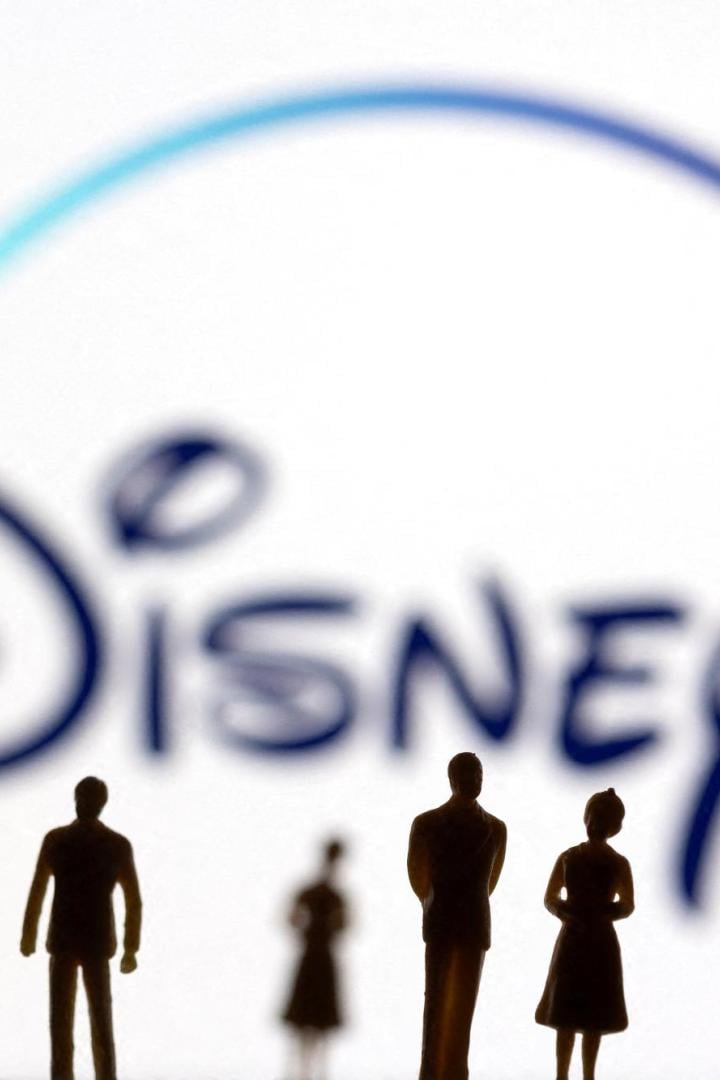 FILE PHOTO: Toy figures of people are seen in front of the displayed Disney + logo, in this illustration