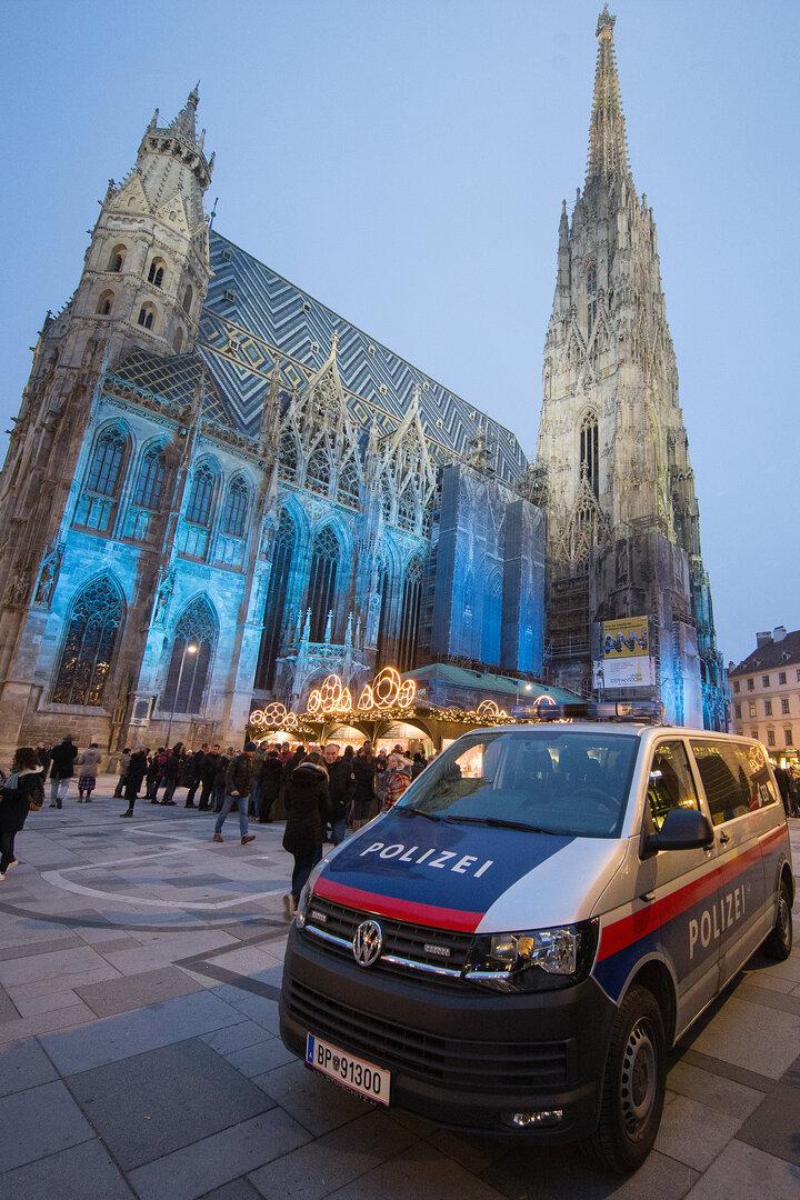 Ein Polizeiwagen steht vor dem beleuchteten Stephansdom in Wien.