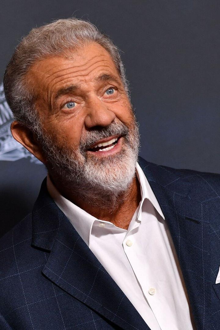 Mel Gibson lächelt in einem dunkelblauen Anzug.