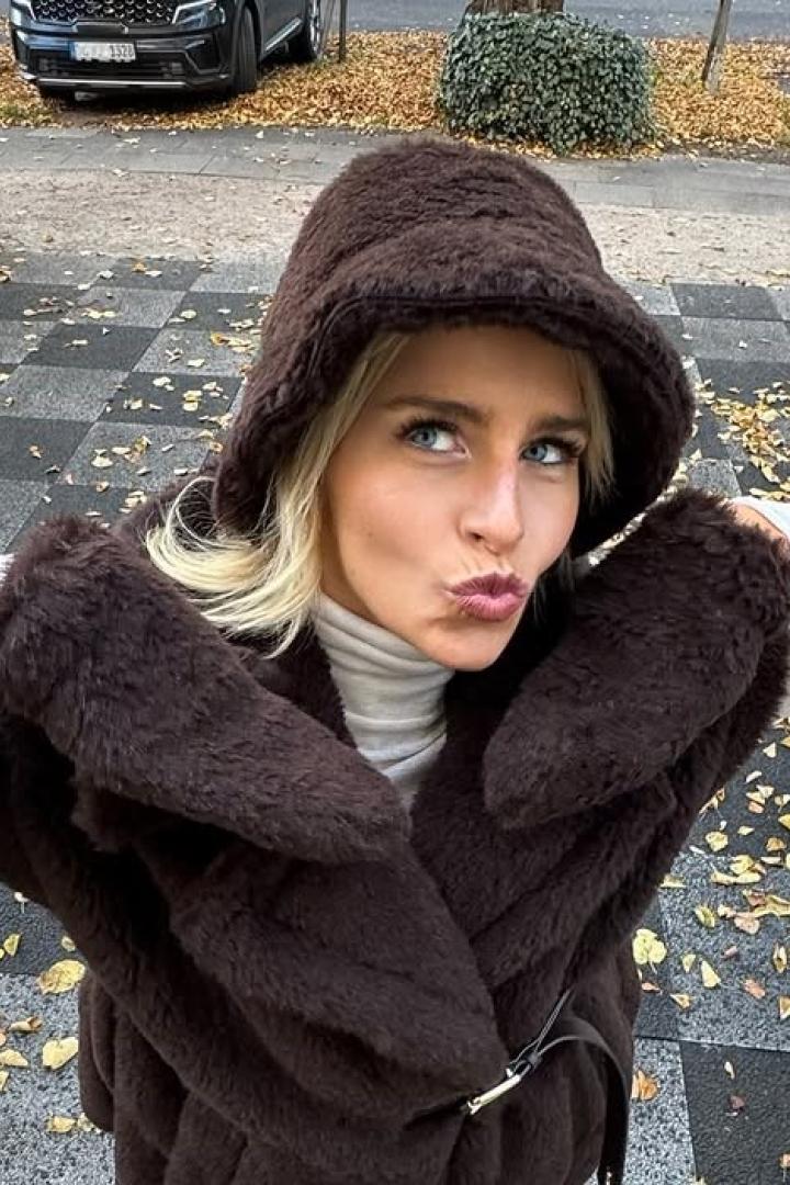 Caro Daur, eine 29-jährige Blondine, posiert mit braunem Stoffhut und brauner Jacke für ein Selfie.