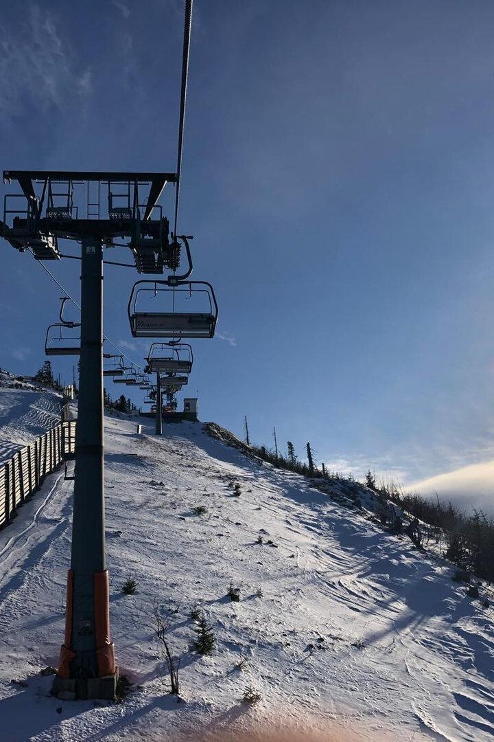 Ein Skilift führt einen verschneiten Hang hinauf, mit blauem Himmel und Sonnenschein.