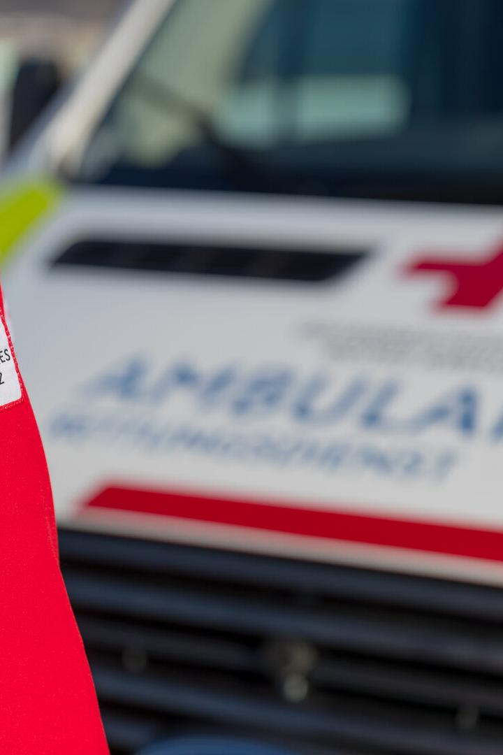 Rettungssanitäter steht vor einem Rot-Kreuz-Auto.