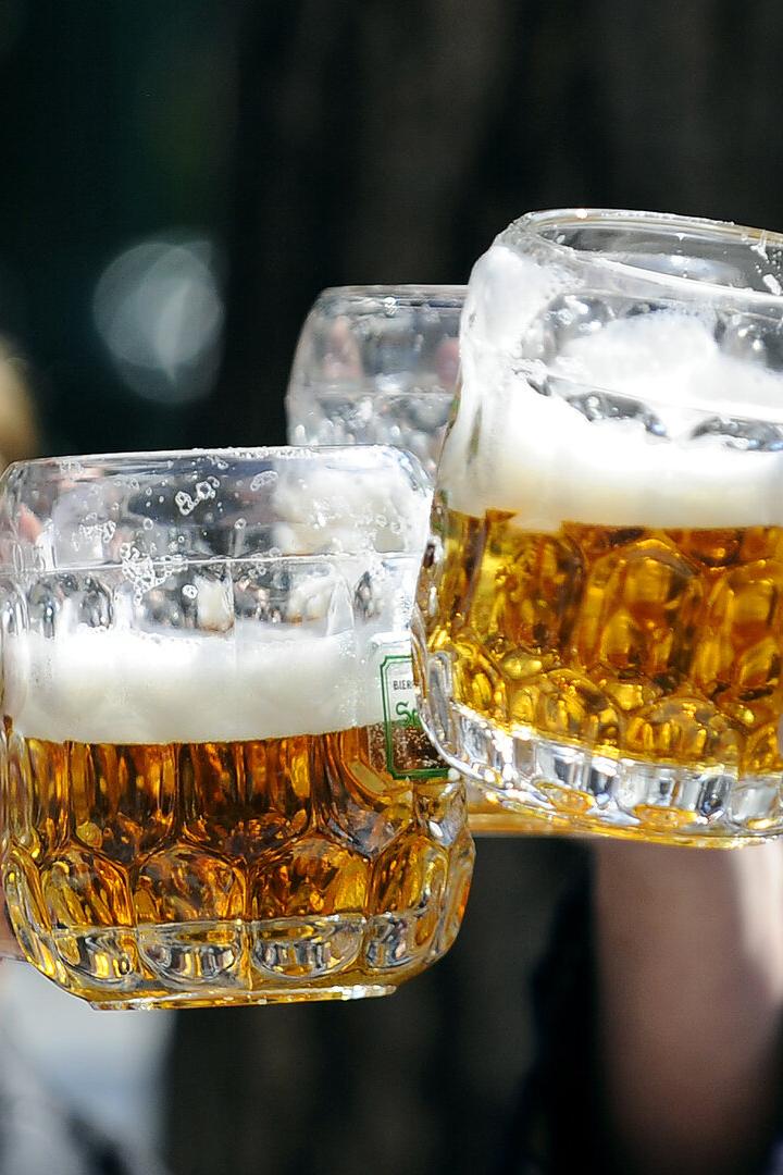 Drei Personen stoßen mit großen Bierkrügen an.