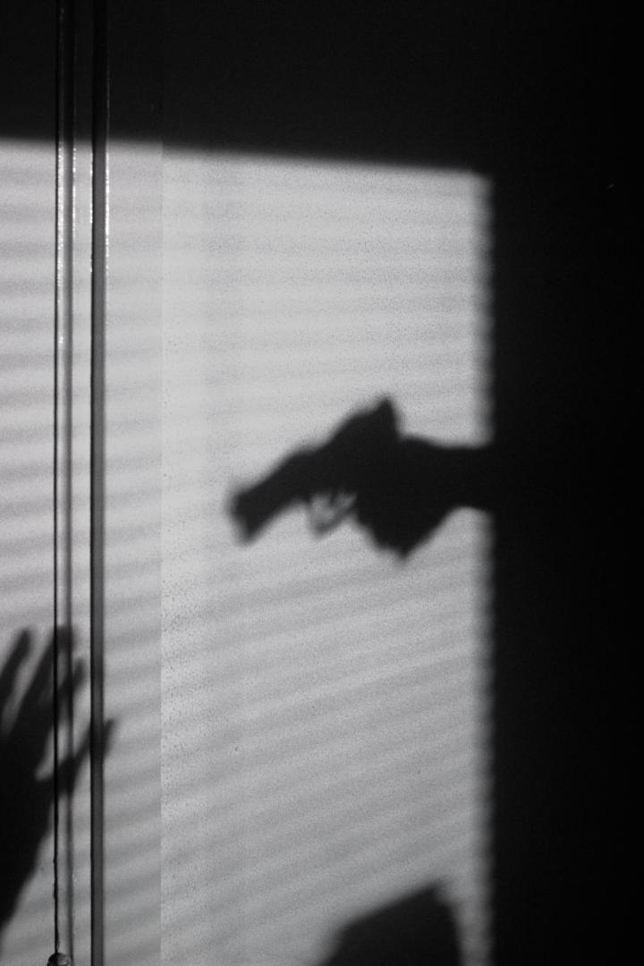 Ein Schatten von einer Pistole und einer Angegriffenen.