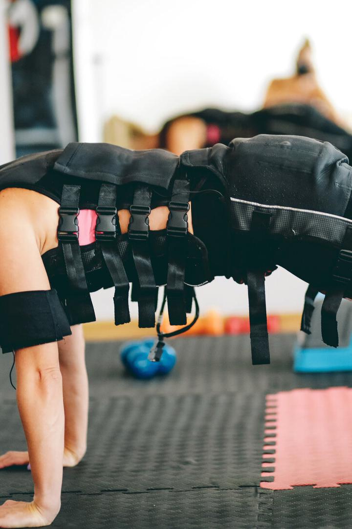 Frau beim EMS-Training: Sie trägt eine Weste, die elektrische Impulse abgibt.