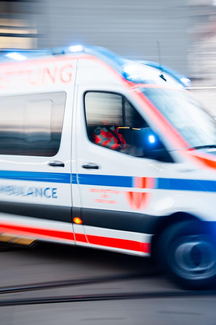 Ein Krankenwagen mit Blaulicht fährt schnell durch eine Stadt.