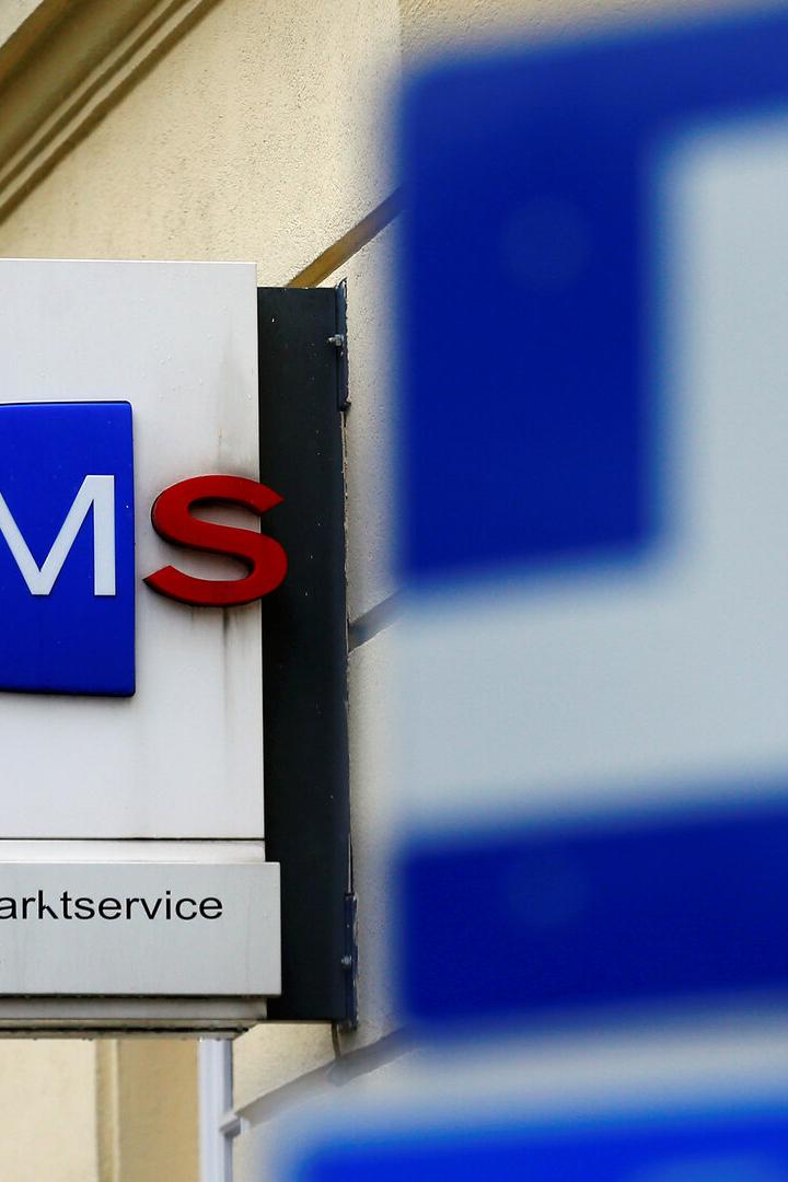 The logo of AMS jobcentre is seen behind traffic signs in Vienna