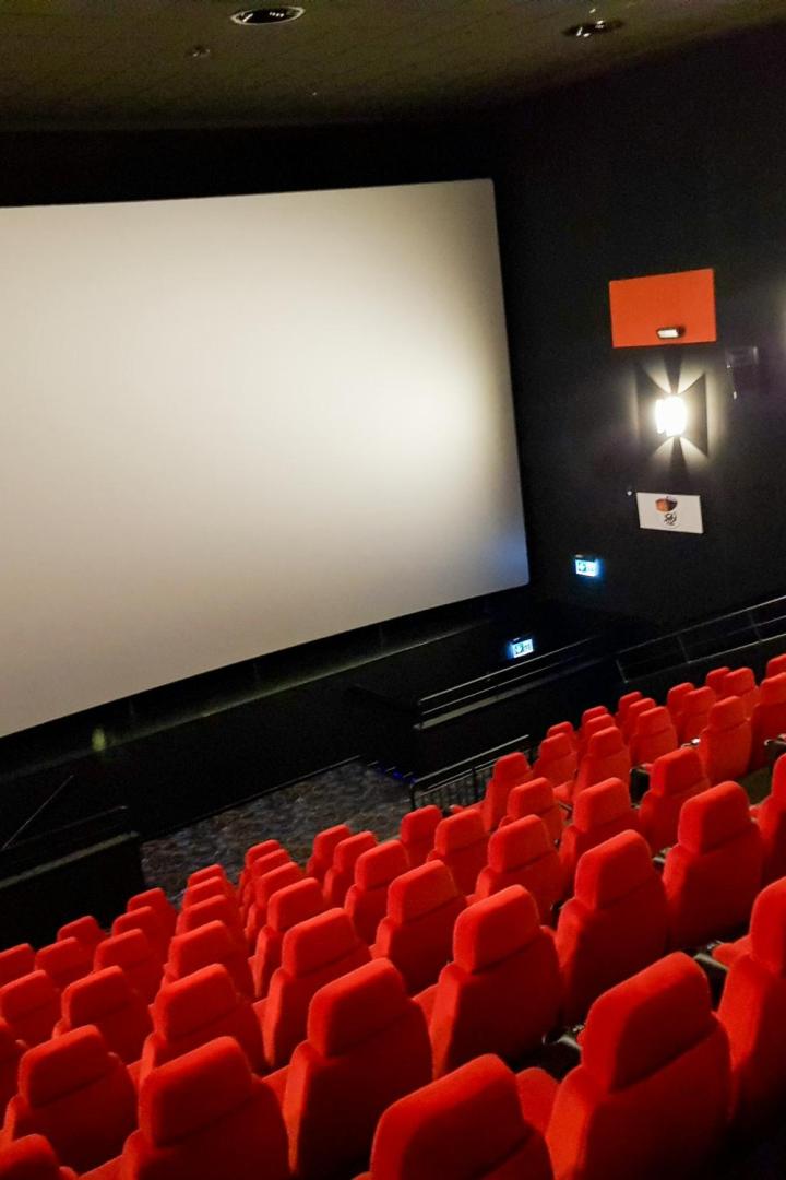 Kinosaal mit roten Sitzen und weißer Leinwand