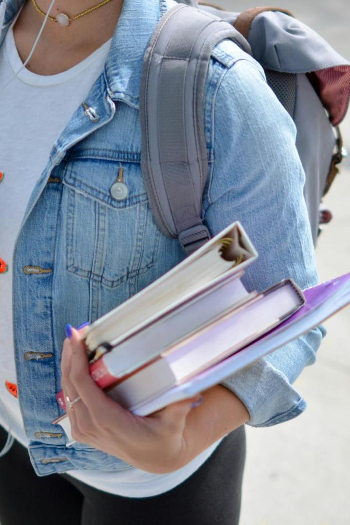 Mädchen mit Jeansjacke hält Bücher in der Hand