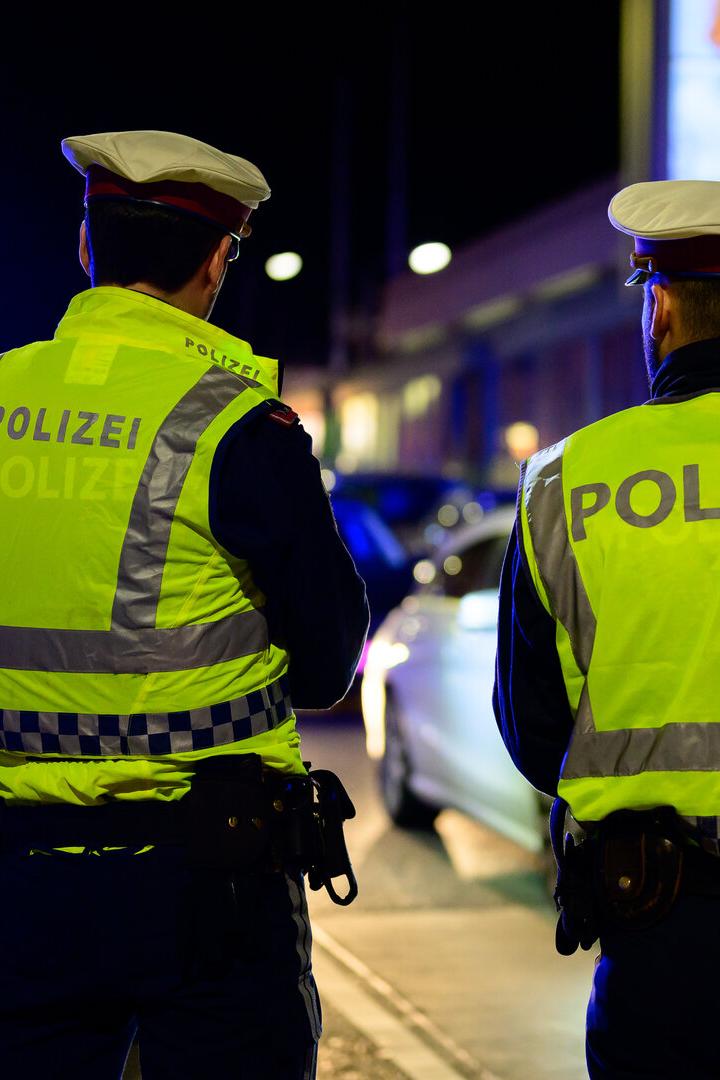Polizisten stehen nachts vor ihren Polizeiautos.