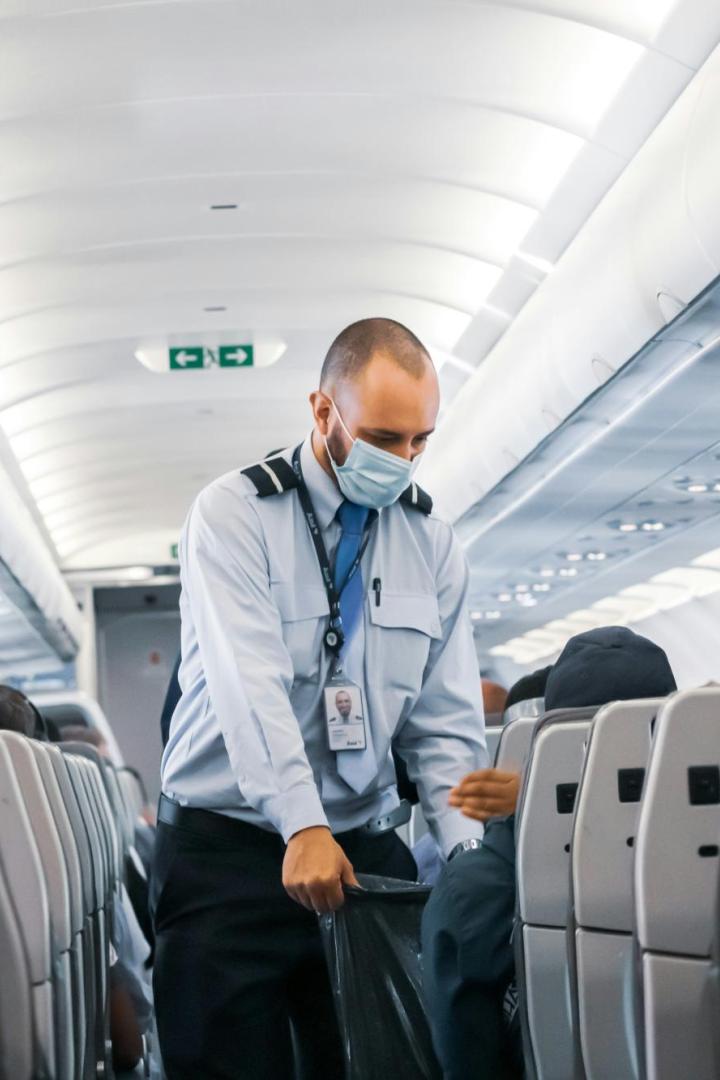 Männliches Crew-Mitglied eines Flugzeugs geht durch die Reihen