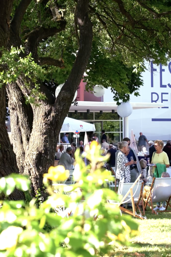 Außenbereich der Festspiele Reichenau, Veranstaltung mit Stühlen im Grünen zwischen Bäumen 