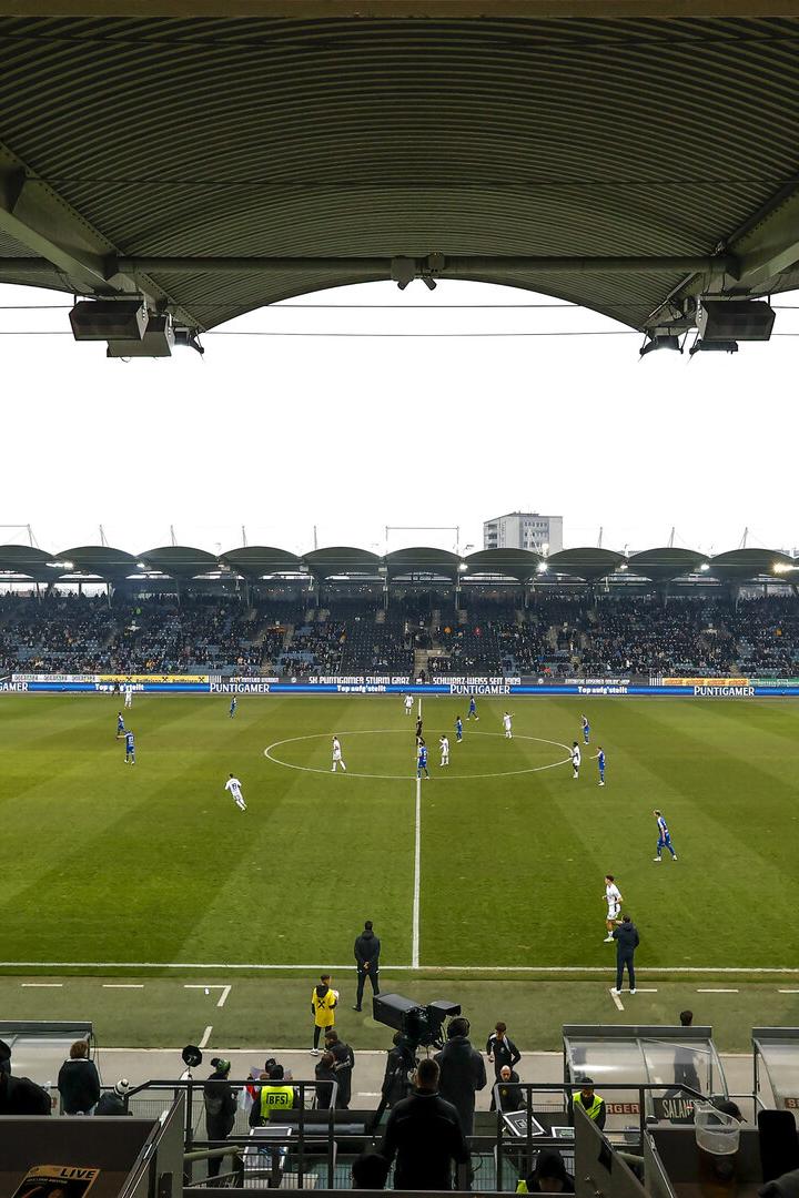 Blick von der Tribüne auf ein Fußballspiel in einem Stadion mit Zuschauern.
