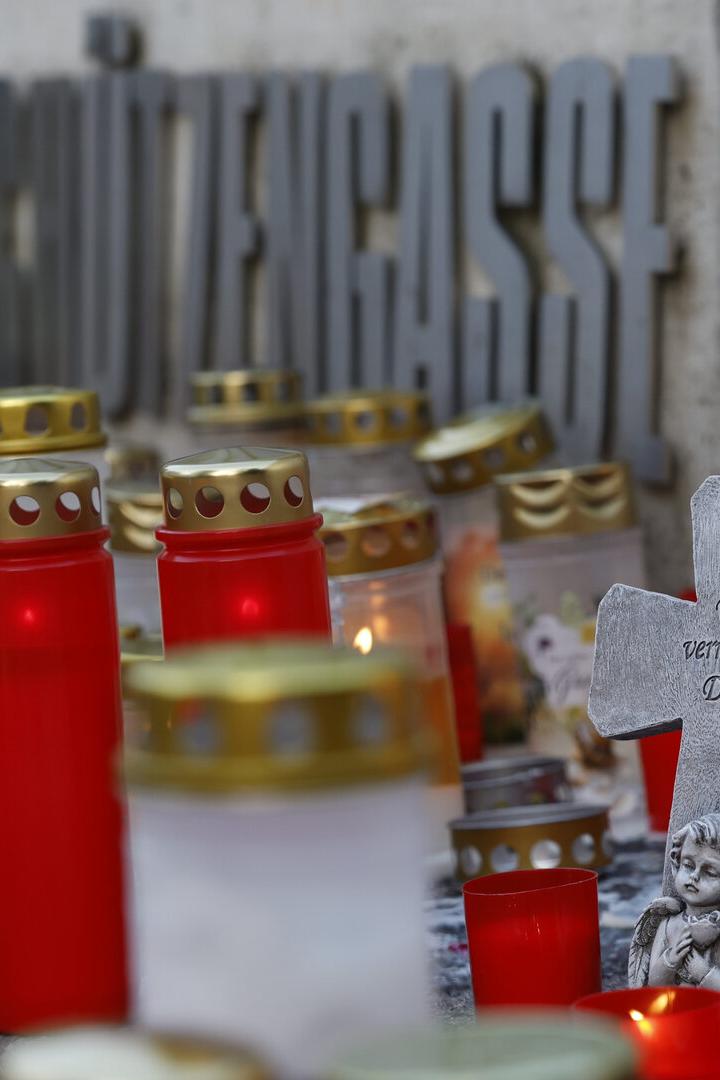 Kerzen und ein Kreuz mit der Aufschrift „Wir vermissen Dich“ vor einem Schulgebäude.