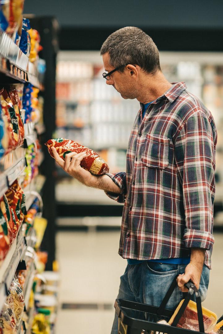 Ein Mann liest ein Etikett, während er in einem Supermarkt einkauft.