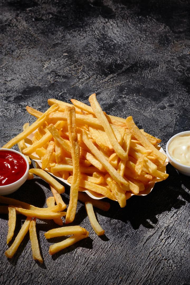 French fries in fryer basket on dark background
