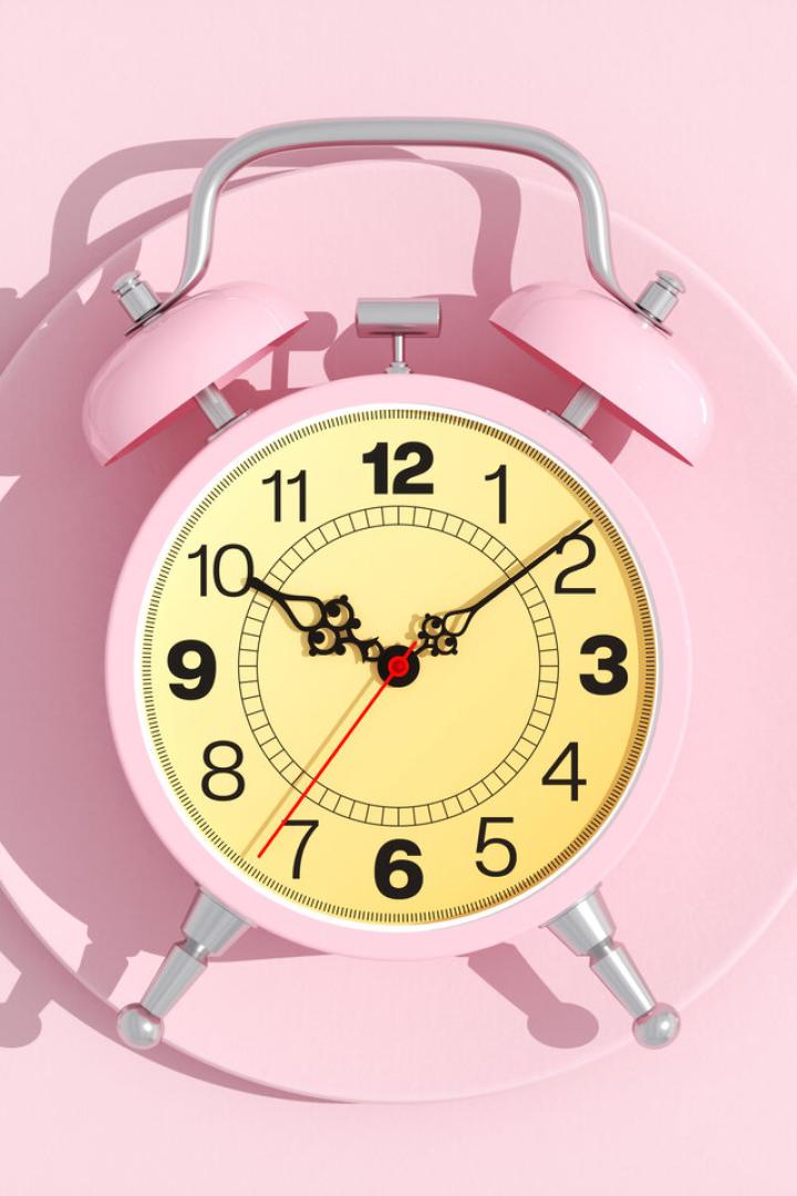 Wecker liegt auf einem Essteller, links und rechts Löffel und Gabel.