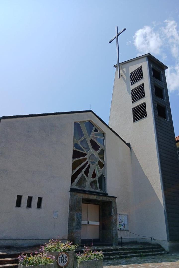 Eine moderne Kirche mit einem Turm und einem Kreuz unter blauem Himmel.
