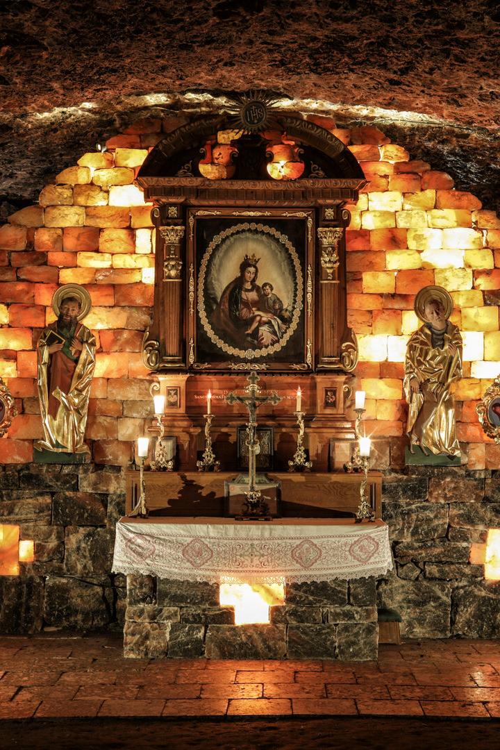 Eine Kapelle in einer Höhle, geschmückt mit Heiligenstatuen und einem Marienbild.