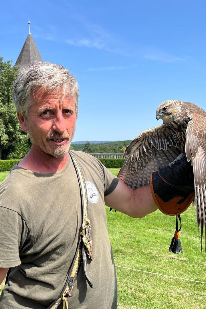 Valdimir Garaj hält einen Falken in seiner Hand und steht auf einer grünen Wiese.