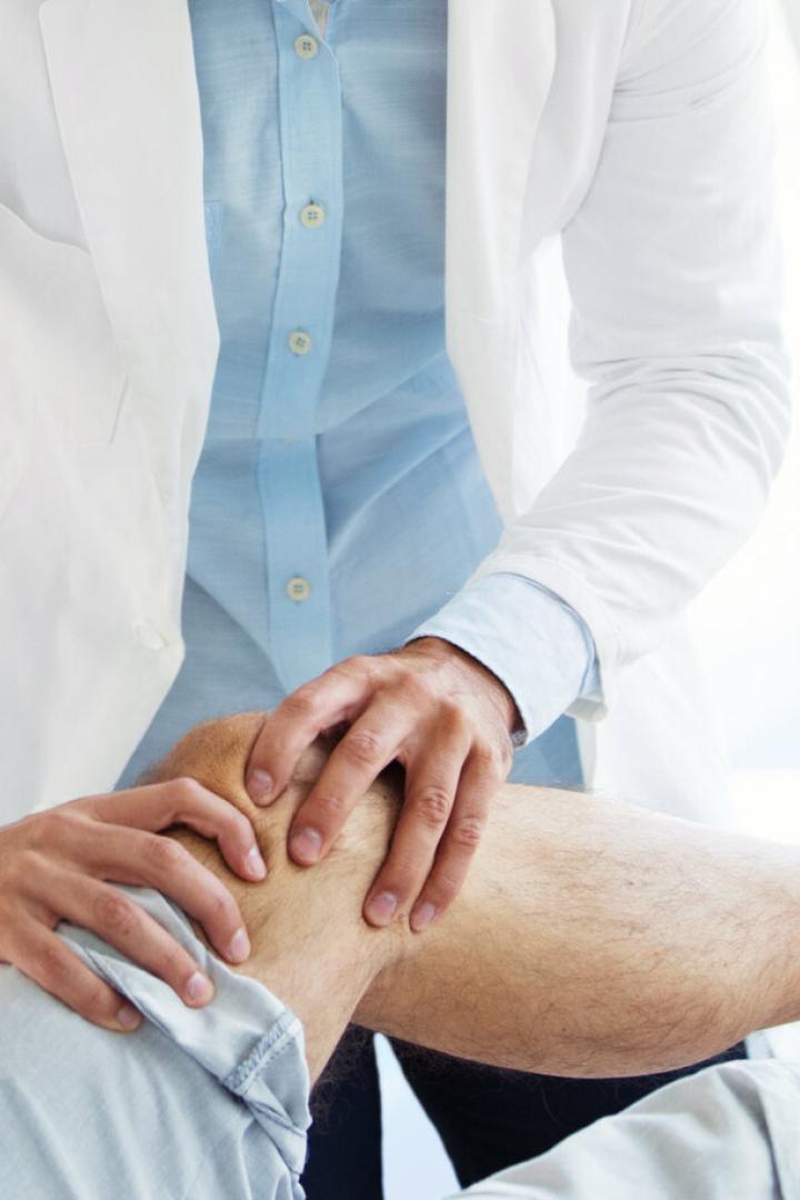 Arzt untersucht Knie eines älteren Mannes.