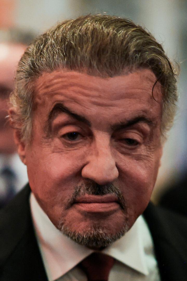 Sylvester Stallone, im verschwommenen Hintergrund Männer