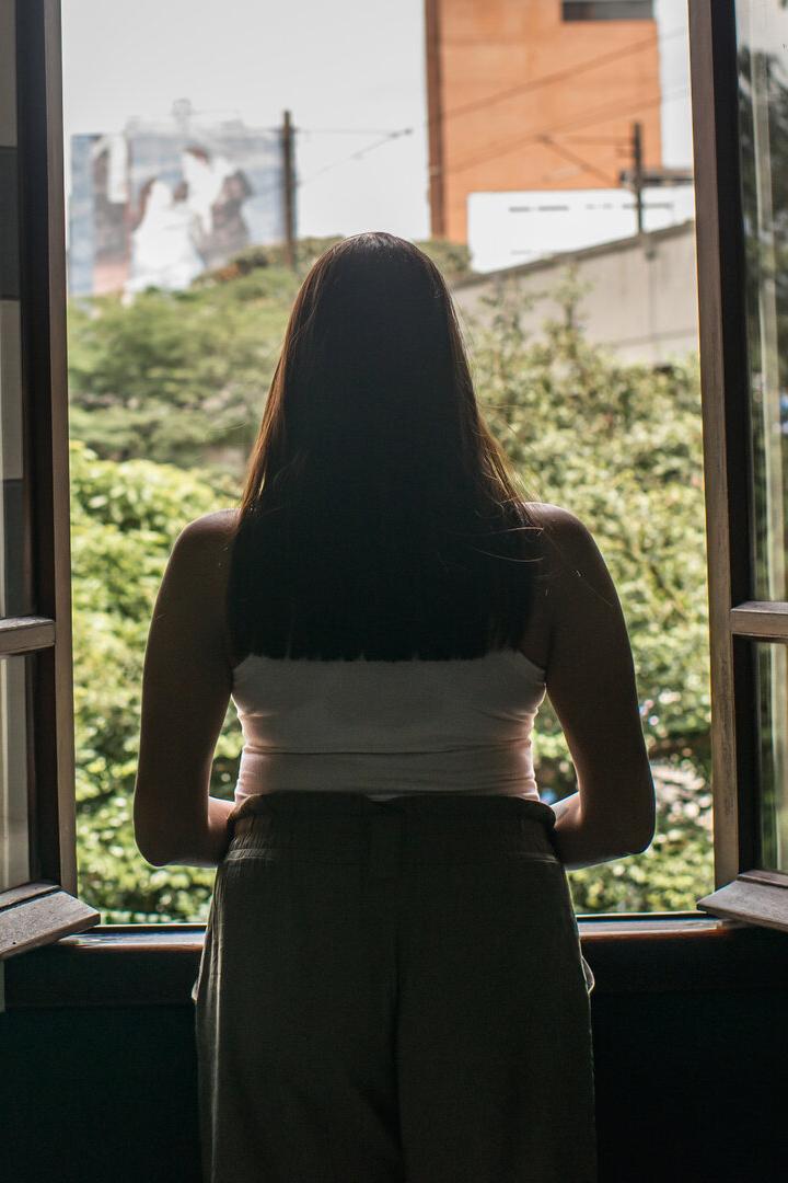 Junge Frau schaut aus dem Fenster.