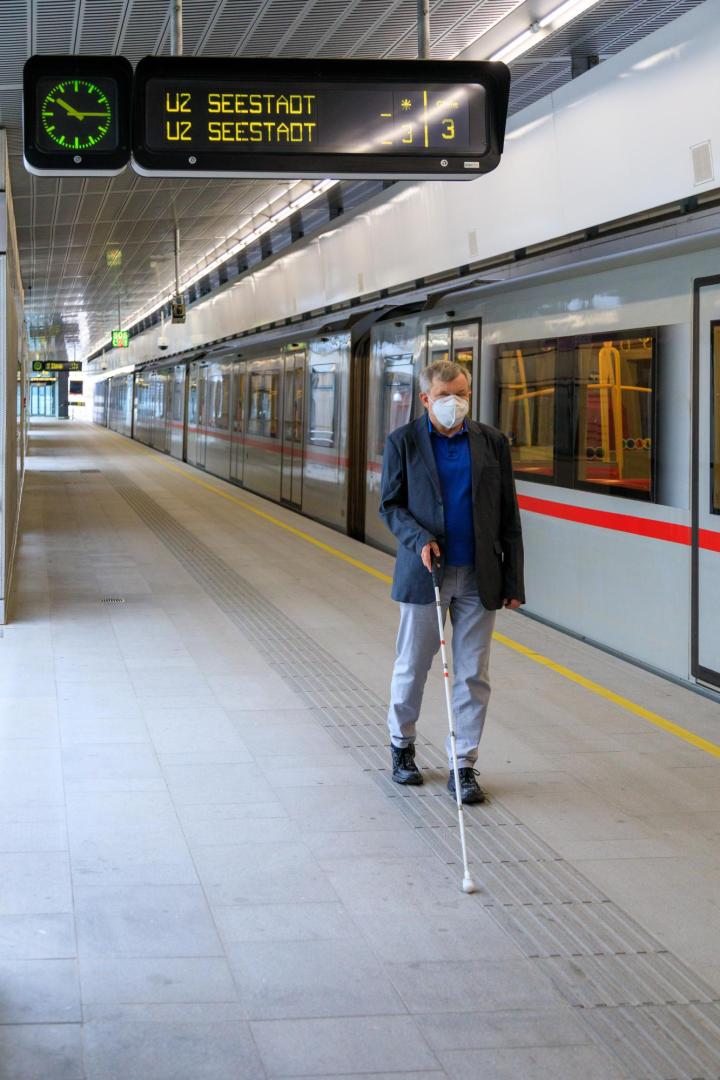 Blinder mit Stock neben U-Bahn.