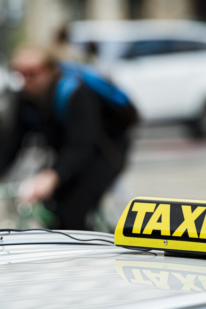 Ein gelbes Taxischild auf dem Dach eines Taxis im Stadtverkehr.