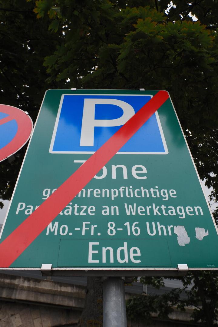 Grünes Verkehrsschild mit rotem Strich und Schrift