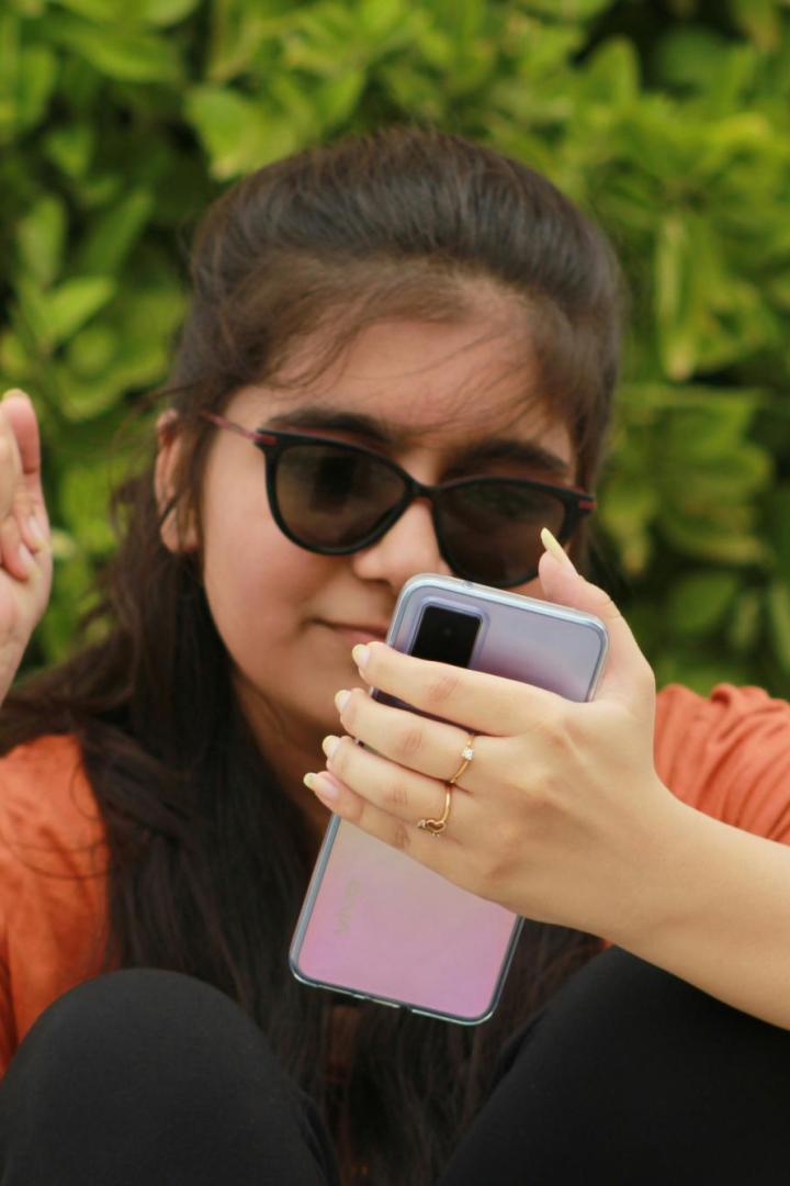 Mädchen mit Sonnenbrille hat Handy in der Hand