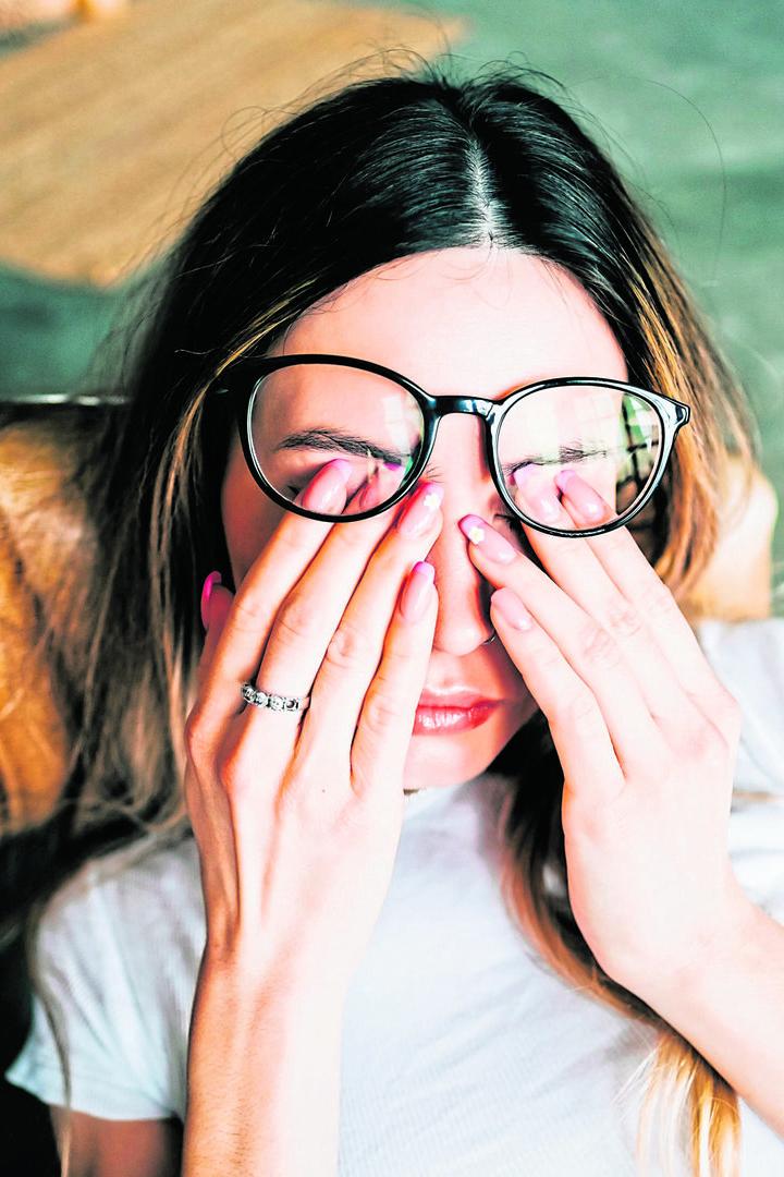 Young woman rubs her eyes after using glasses. Eye pain or fatigue concept.