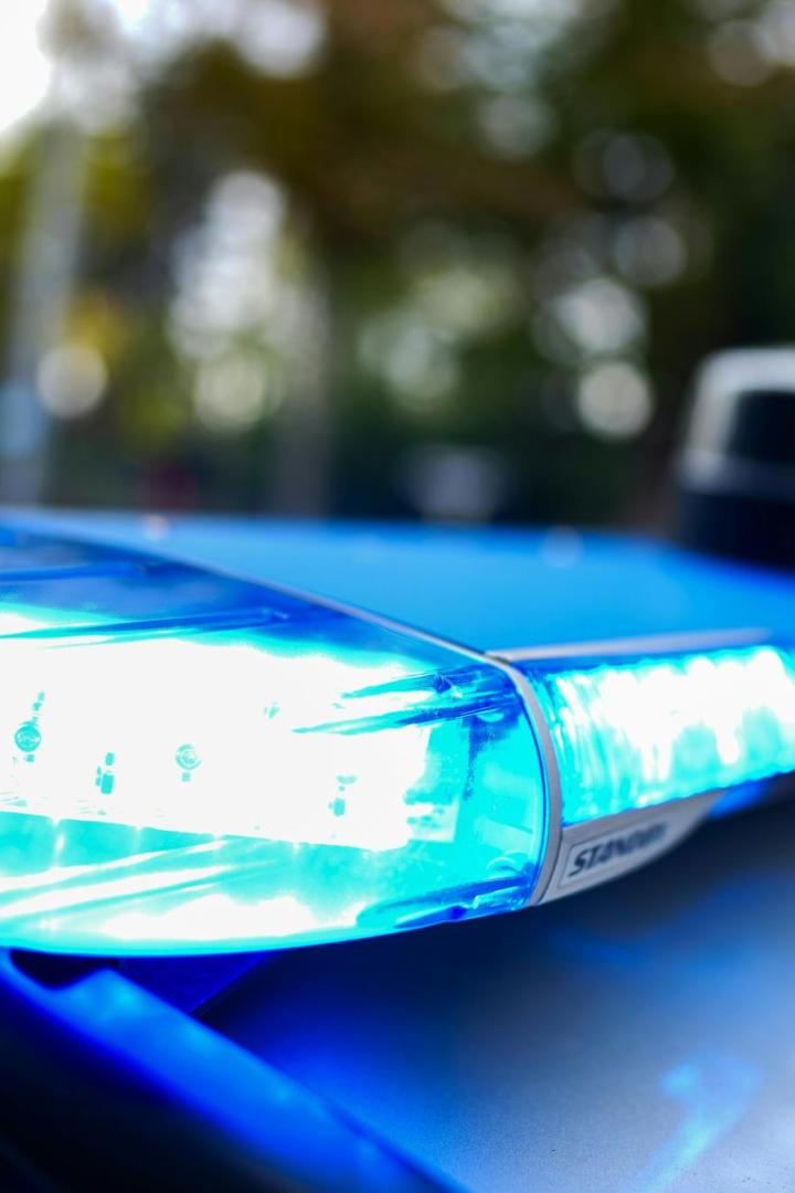 Blaulicht auf dem Dach eines Einsatzfahrzeugs leuchtet hell im Vordergrund.