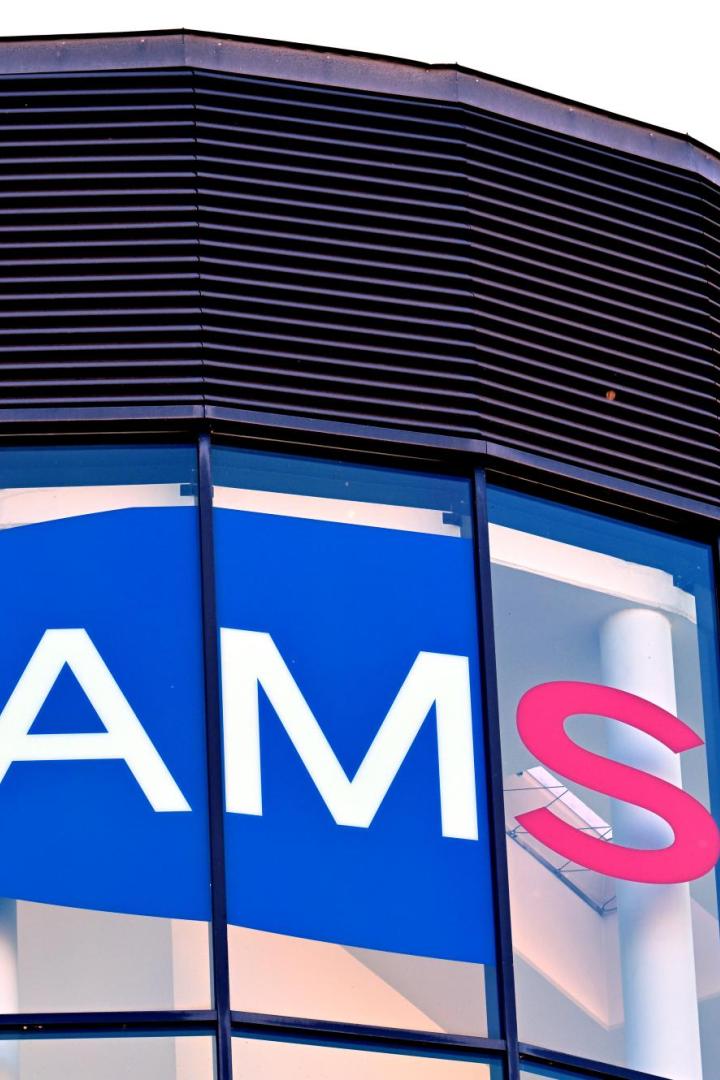 Große Glasfassade mit dem Schriftzug „AMS“ in Weiß und Rot auf blauem Hintergrund.
