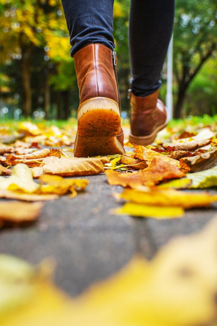 legs of a woman in brown boots walking in a park