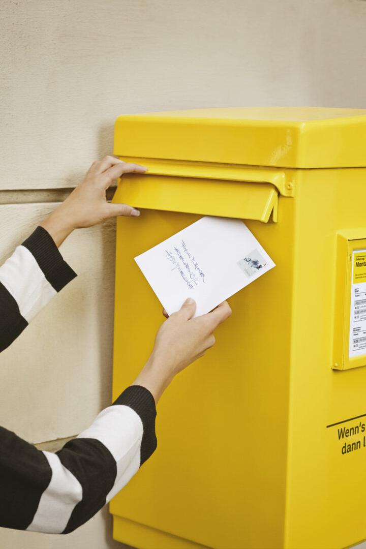 Eine Frau wirft einen Brief in einen Briefkasten