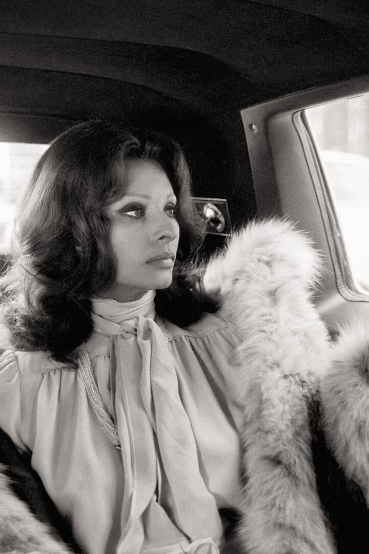 Sophia Loren im Auto, sie hat einen Pelzmantel an und sieht zum Fenster hinaus