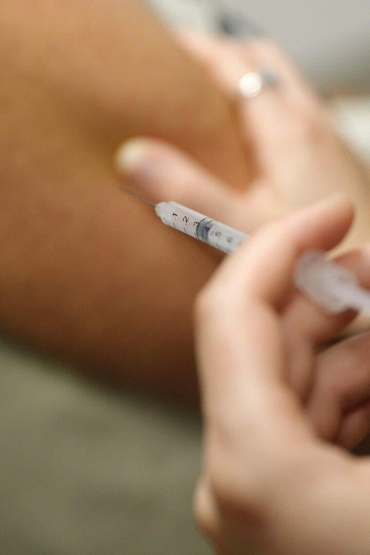 Eine Person erhält eine Injektion mit einer Spritze in den Oberarm.