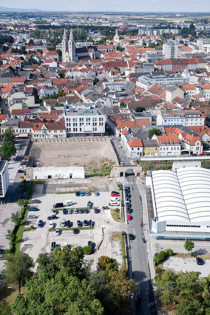 Die Aufnahme zeigt einen Blick auf Wiener Neustadt mit Gebäuden, Parkplätzen und Grünflächen.
