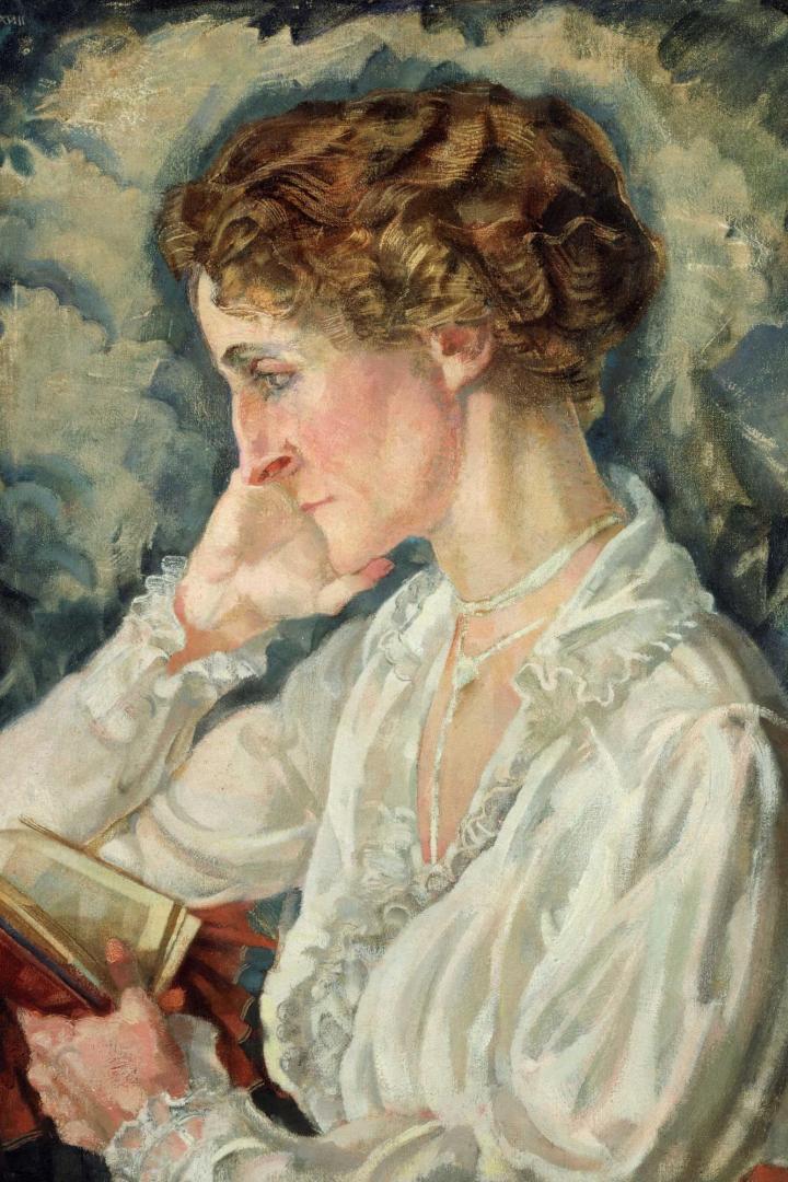 Frau mit hochgestecktem, gewelltem Haar trägt weiße, rüschenverzierte Bluse und hält ein aufgeschlagenes Buch in der Hand.