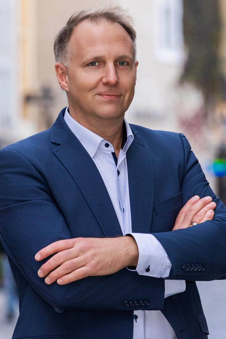 Mann im Anzug mit verschränkten Armen auf einer Straße