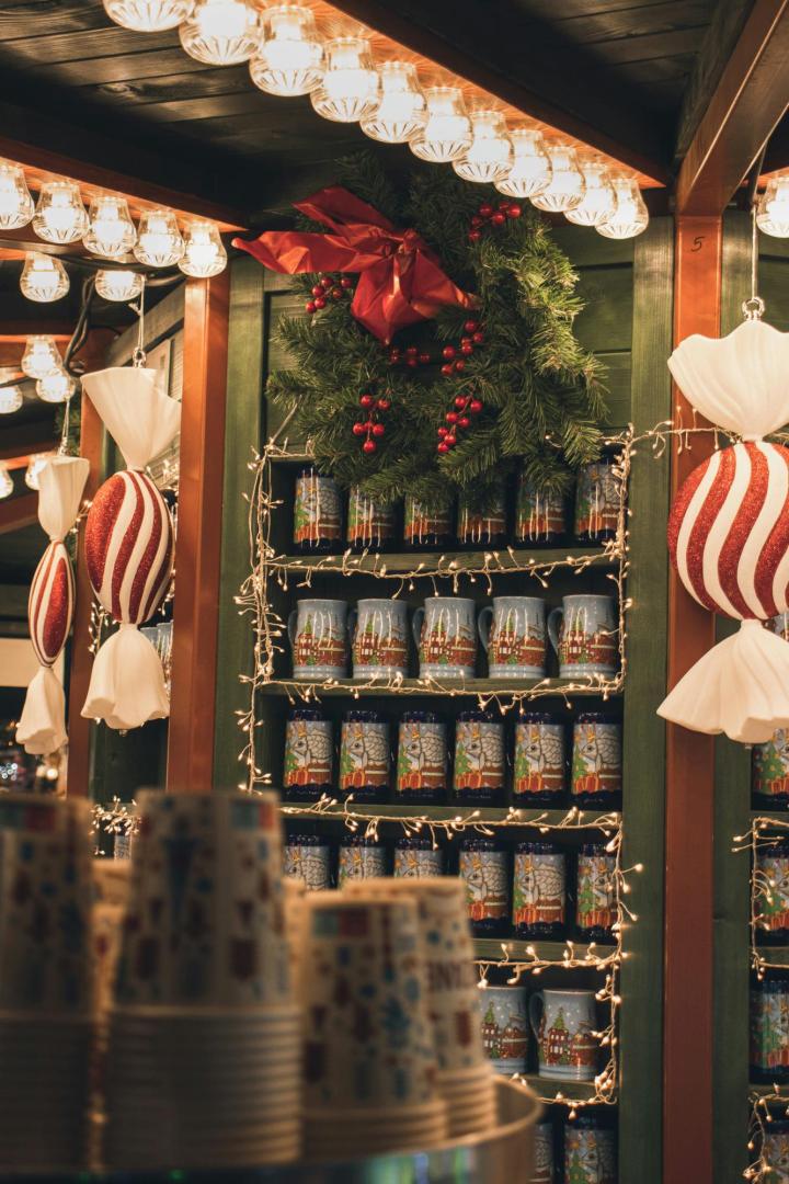 Regale mit bunten Glühweinhäferln, Lichterketten und Weihnachtsdekoration auf dem Christkindlmarkt.