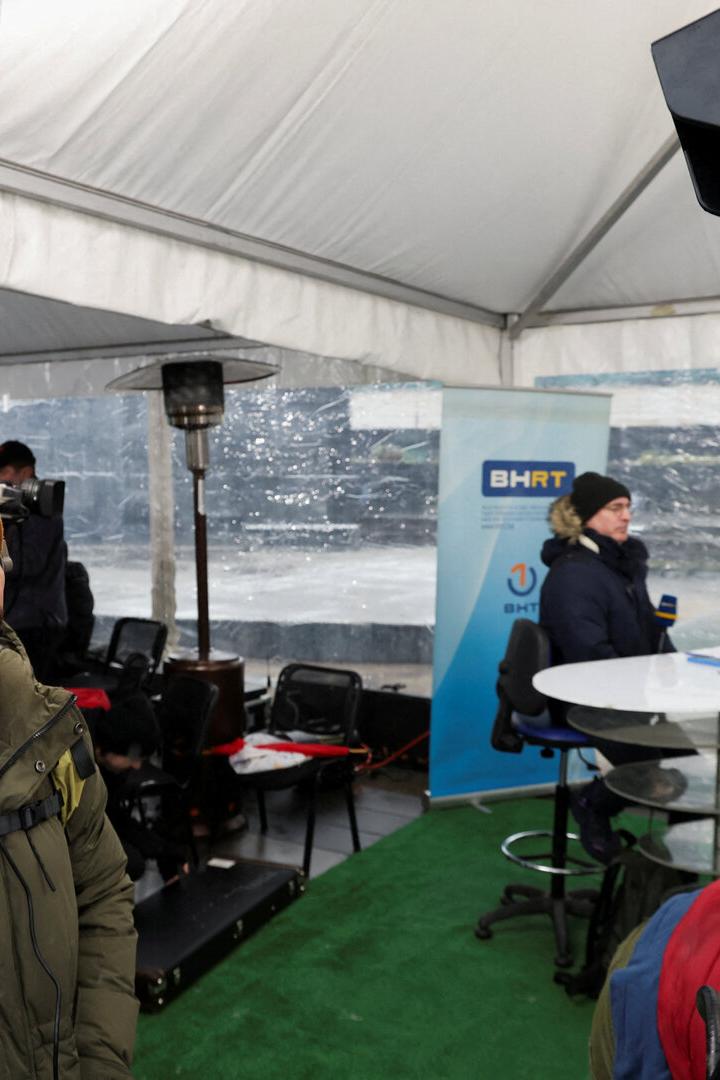 Ein Mann mit Mütze schaut in ein Zelt, wo ein Interview für BHRT gefilmt wird.