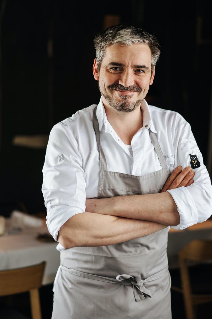Manuel Ressi, der Koch vom Bärenwirt,  mit verschränkten Armen steht vor einem gedeckten Tisch.