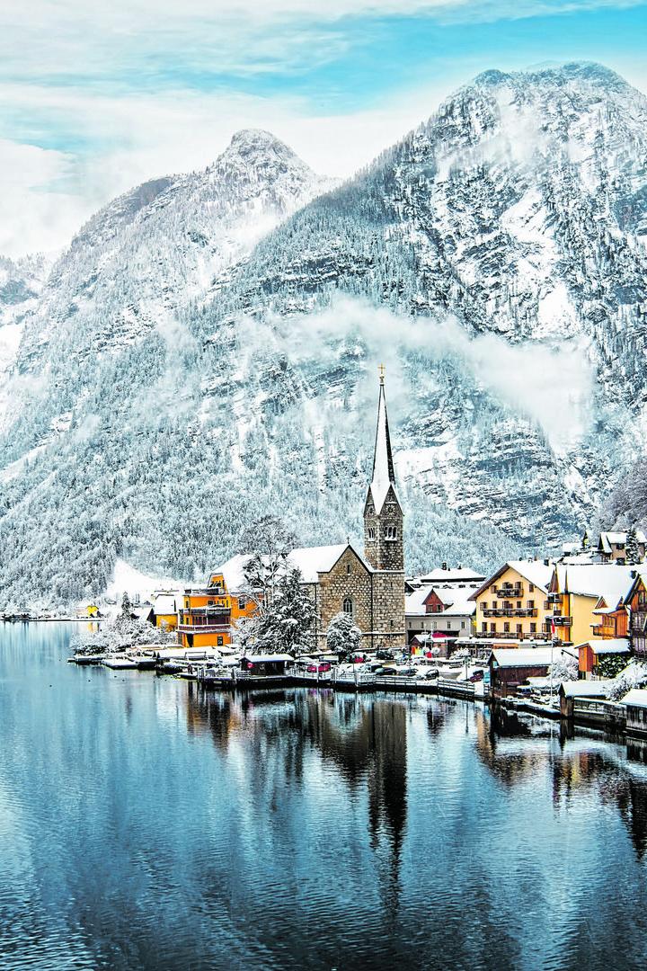 Winterliches Hallstatt mit schneebedeckten Bergen und Häusern am See.