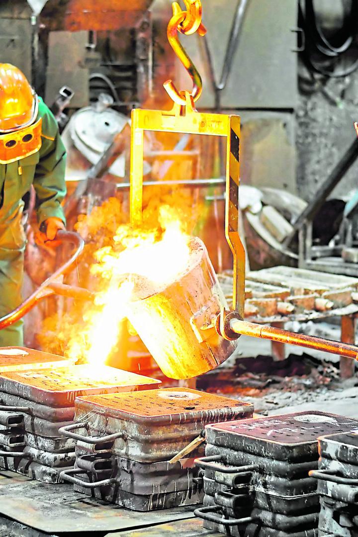 Group of workers in a foundry at the melting furnace - production of steel castings in an industrial company