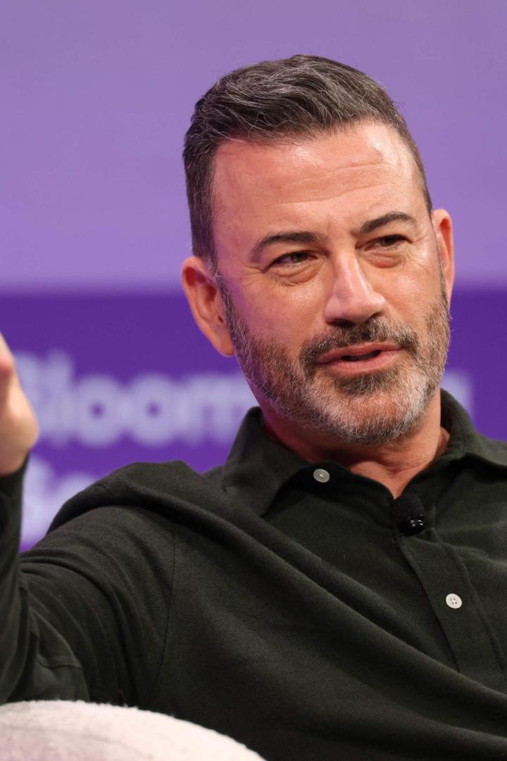 Jimmy Kimmel gestikuliert vor einem lila Hintergrund.