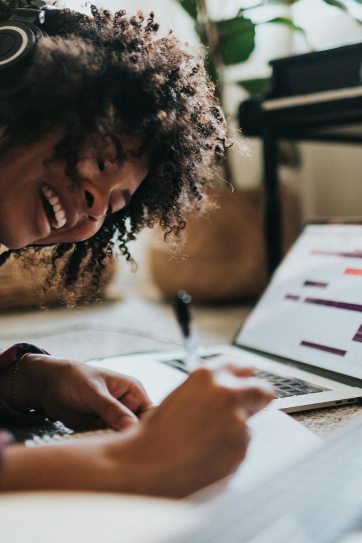 Frau hört lachend Musik vor einem Laptop