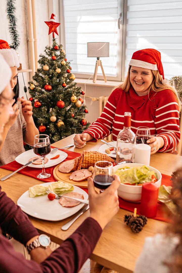 Menschen sitzen zusammen beim Tisch bei einem Weihnachtsessen.